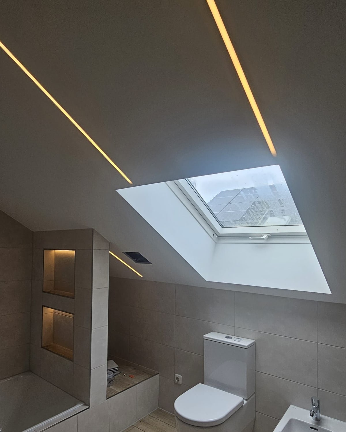 Bad unter der Dachschräge mit LED-Lichtprofilen, Dachfenster und Wand-WC